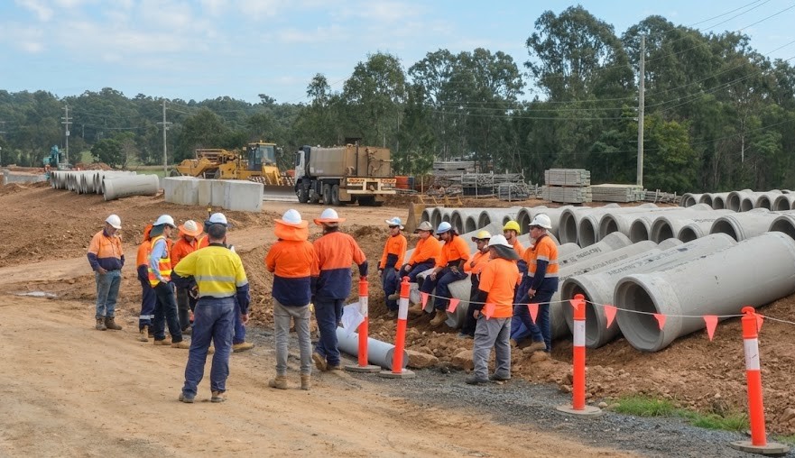 QBC site crew in workwear gathered for a toolbox talk - direct, respectful communication in action